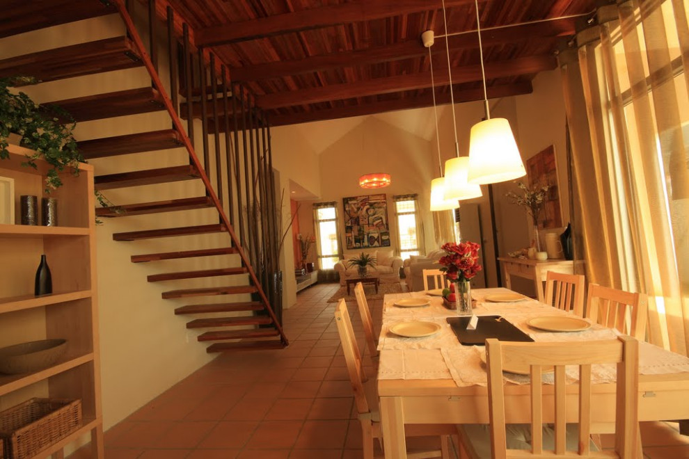 Foto di una piccola sala da pranzo aperta verso il soggiorno rustica con pareti beige, pavimento in terracotta, pavimento arancione e soffitto in perlinato