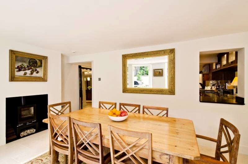 Exemple d'une grande salle à manger ouverte sur la cuisine tendance avec un sol en calcaire, un poêle à bois et un manteau de cheminée en plâtre.