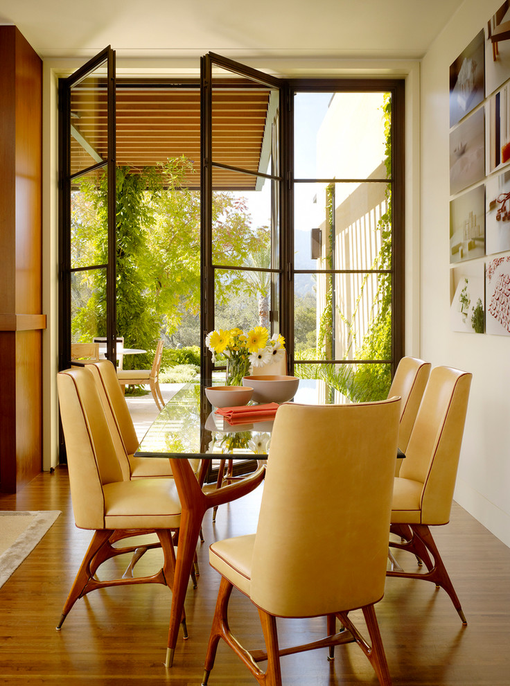 Immagine di una sala da pranzo aperta verso la cucina mediterranea con pareti bianche e pavimento in legno massello medio