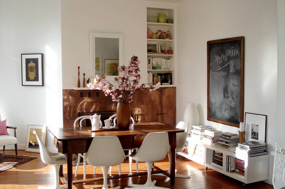 Cette photo montre une salle à manger éclectique avec un mur blanc et un sol en bois brun.