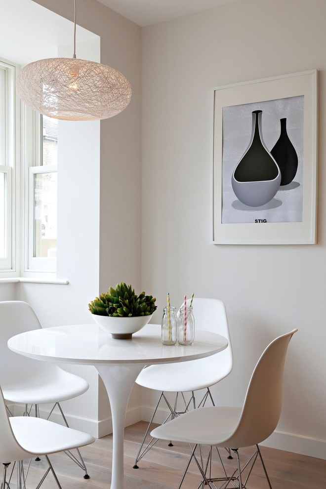 На фото: кухня-столовая в скандинавском стиле с белыми стенами и светлым паркетным полом
