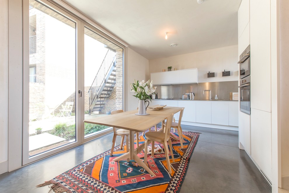 Cette photo montre une salle à manger ouverte sur la cuisine scandinave avec un mur beige, sol en béton ciré et un sol gris.