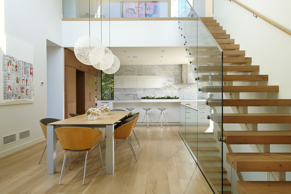 Cette image montre une salle à manger ouverte sur le salon design avec un mur blanc et parquet clair.