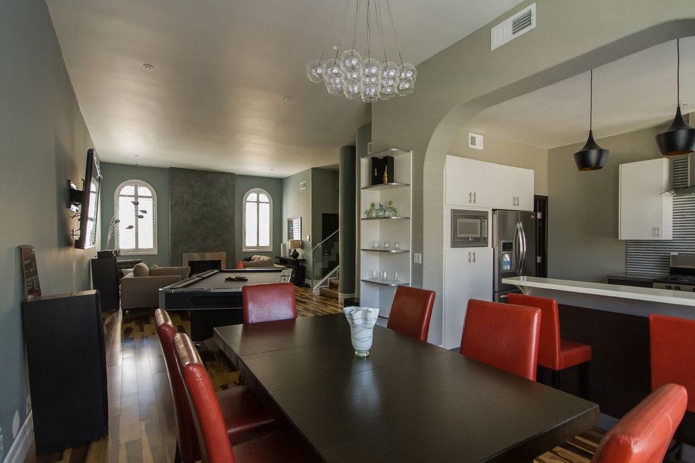 На фото: большая гостиная-столовая в стиле модернизм с серыми стенами, темным паркетным полом и коричневым полом без камина с