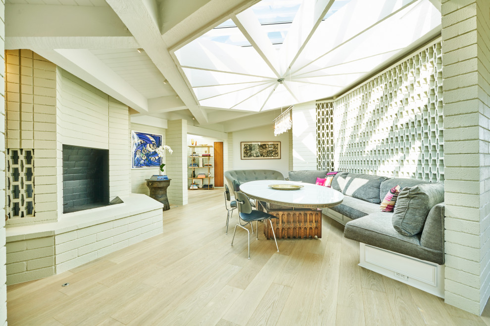 Mittelgroße Mid-Century Wohnküche mit weißer Wandfarbe, hellem Holzboden, Eckkamin, Kaminumrandung aus Backstein und beigem Boden in Los Angeles
