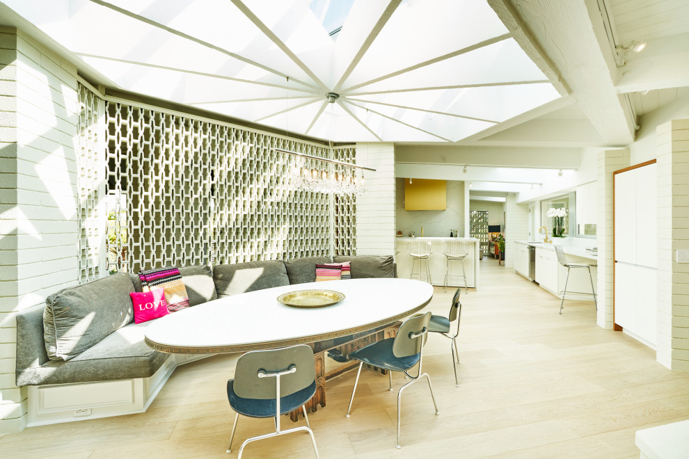 Idee per una sala da pranzo aperta verso la cucina moderna di medie dimensioni con parquet chiaro, pavimento beige, pareti bianche, camino ad angolo e cornice del camino in mattoni