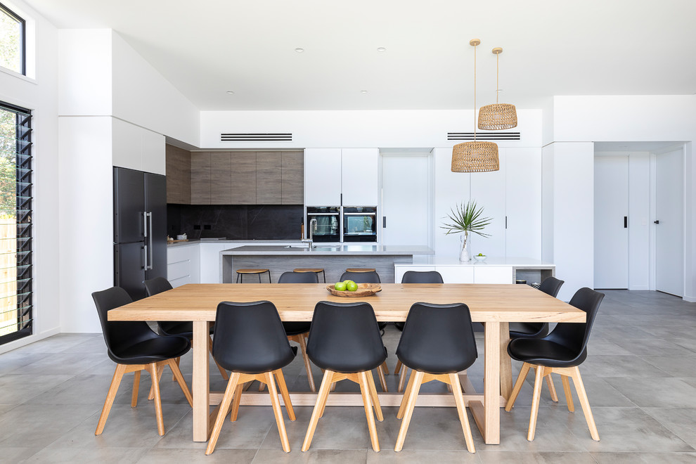 Cette image montre une grande salle à manger ouverte sur la cuisine design avec un mur blanc, un sol en carrelage de céramique et un sol gris.