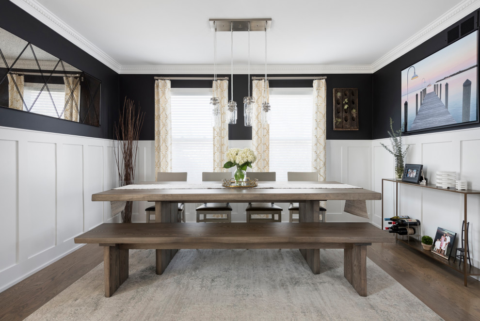 Foto di una sala da pranzo chic di medie dimensioni con pareti nere, pavimento in legno massello medio, pavimento grigio e boiserie