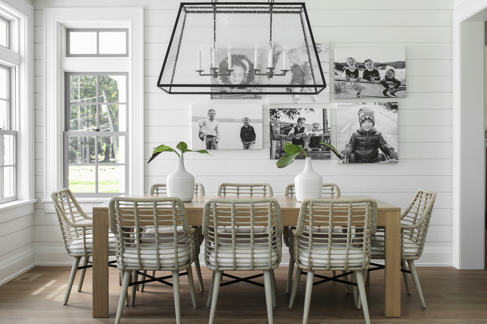 This is an example of a nautical dining room in New York with white walls, medium hardwood flooring and brown floors.