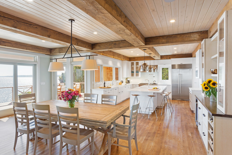 Foto di una grande sala da pranzo aperta verso la cucina stile marinaro con pavimento in legno massello medio, pareti grigie e nessun camino