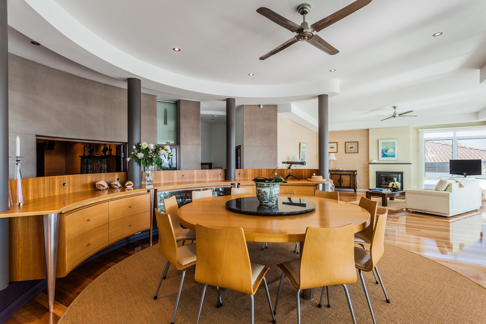 Immagine di una sala da pranzo aperta verso il soggiorno stile marino con pareti grigie e pavimento in legno massello medio