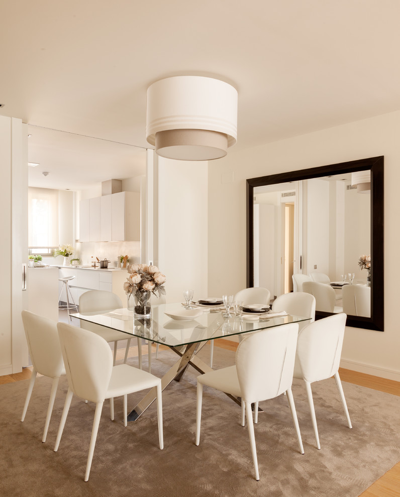 Cette image montre une salle à manger ouverte sur la cuisine design de taille moyenne avec un mur blanc, un sol en bois brun, aucune cheminée et éclairage.