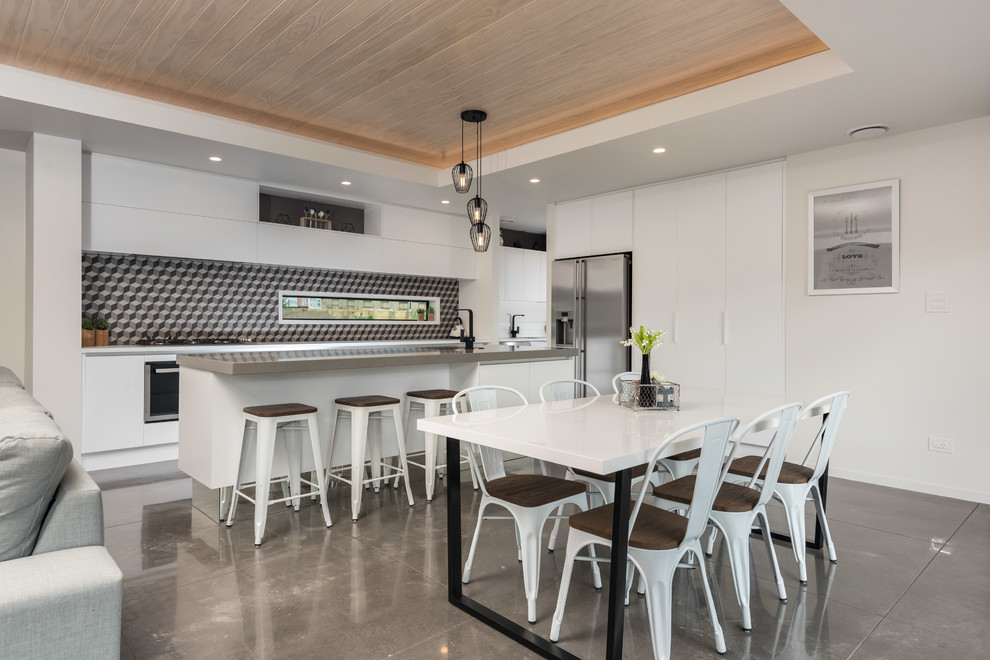 Cette image montre une salle à manger ouverte sur le salon design avec un mur blanc et sol en béton ciré.