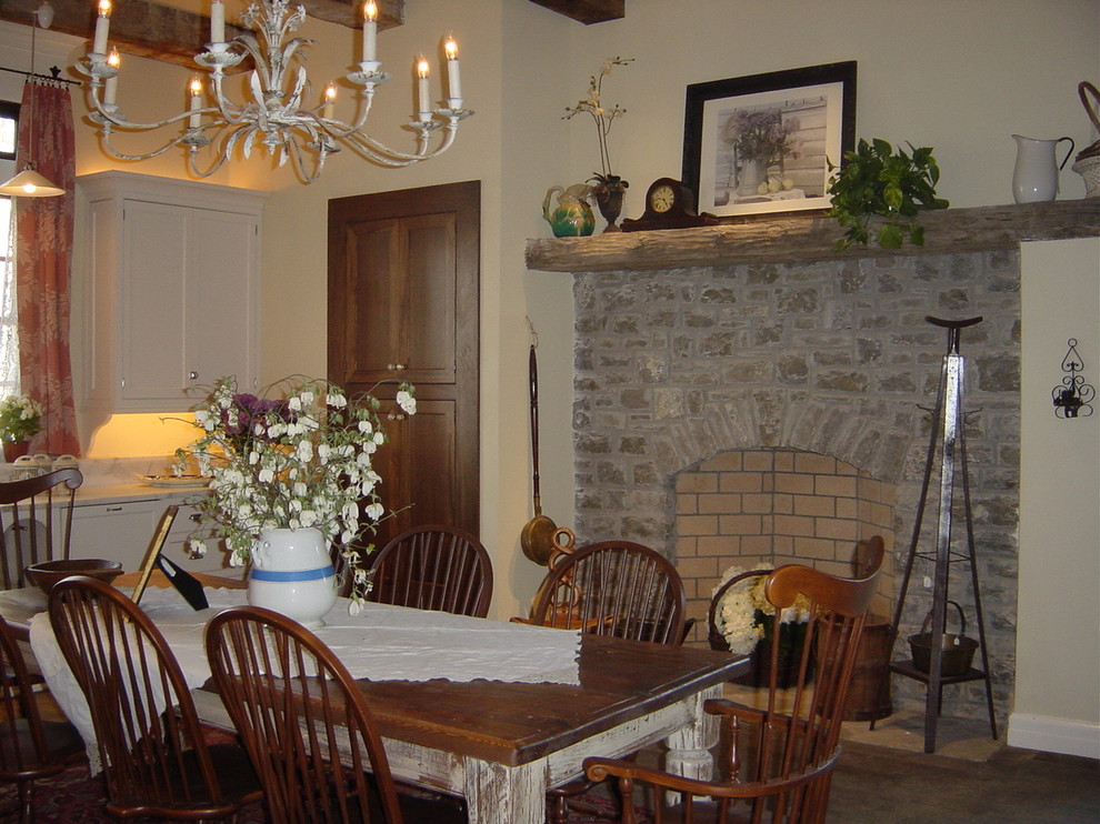 Réalisation d'une salle à manger ouverte sur la cuisine champêtre avec une cheminée standard et un manteau de cheminée en pierre.