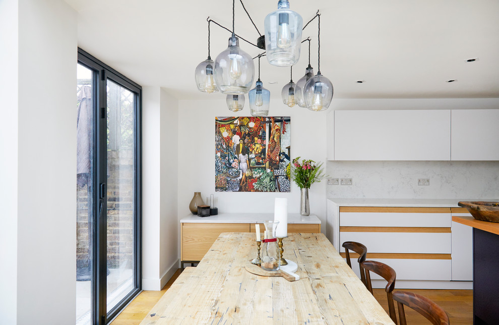 Idée de décoration pour une grande salle à manger ouverte sur la cuisine design avec un sol en bois brun, un sol marron et un mur blanc.