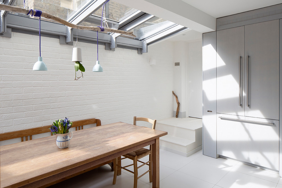 На фото: кухня-столовая среднего размера в скандинавском стиле с белыми стенами, полом из керамогранита и белым полом