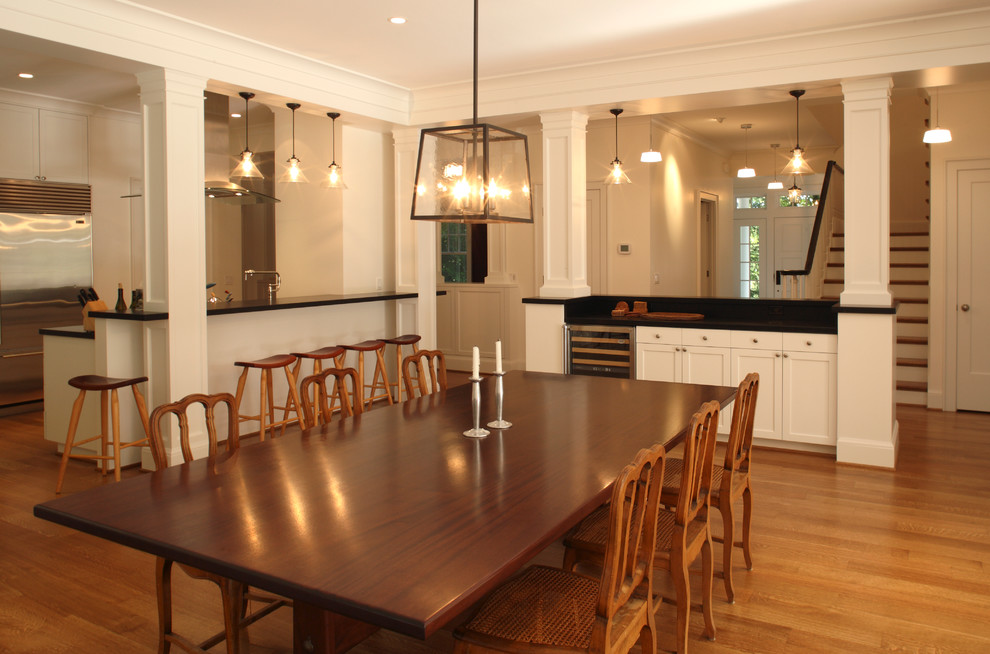 Cette photo montre une grande salle à manger ouverte sur la cuisine chic avec un mur blanc, un sol en bois brun et aucune cheminée.