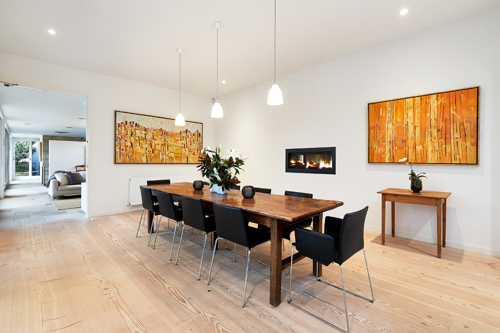 Inspiration for a large modern kitchen/dining room in Melbourne with white walls, light hardwood flooring, a standard fireplace and a metal fireplace surround.