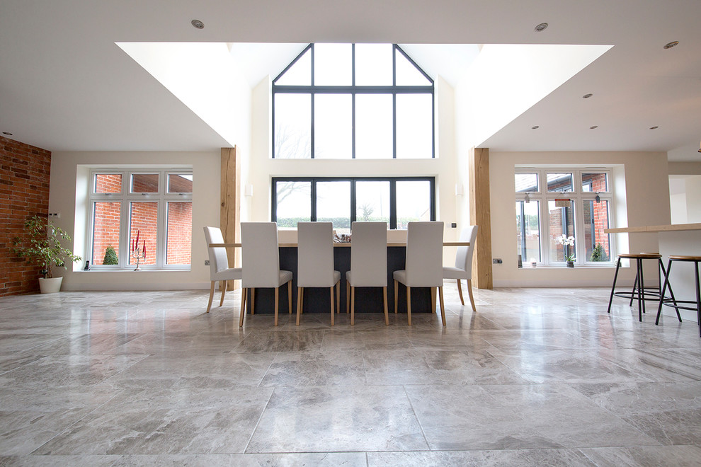 Immagine di un'ampia sala da pranzo aperta verso la cucina design con pareti bianche, pavimento in pietra calcarea e pavimento grigio