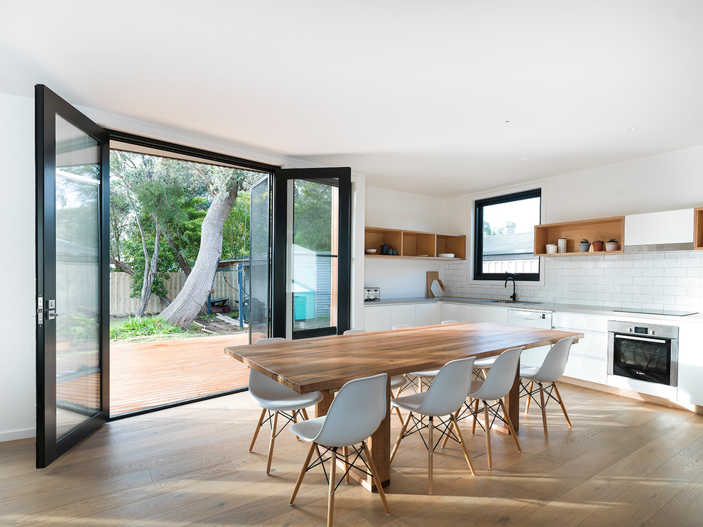 Идея дизайна: кухня-столовая в современном стиле с белыми стенами и светлым паркетным полом