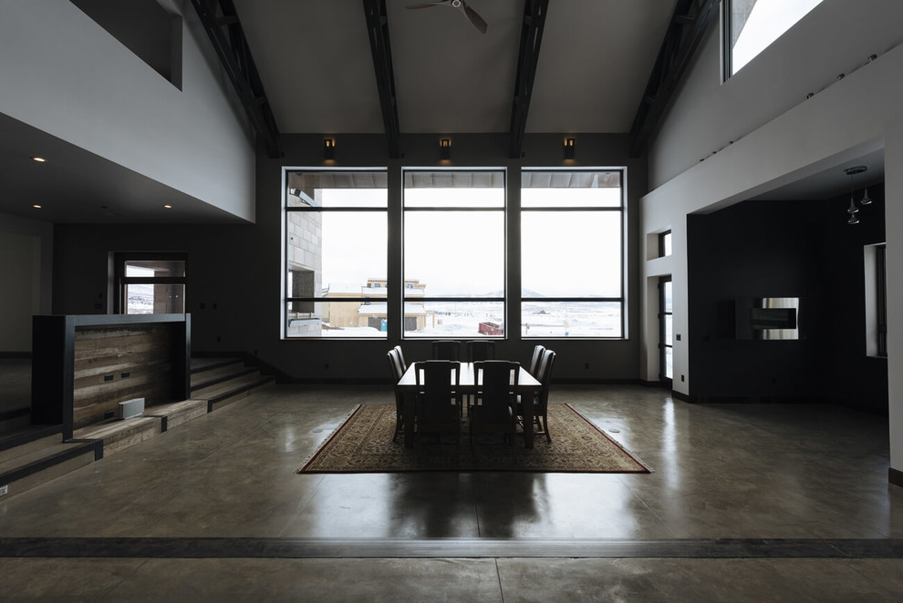 Foto di una sala da pranzo aperta verso il soggiorno minimalista di medie dimensioni con pareti bianche, pavimento in cemento e pavimento grigio