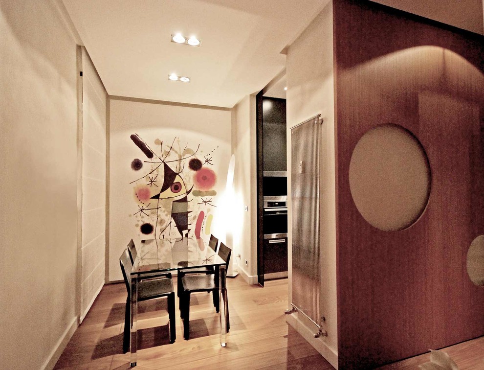 Immagine di una piccola sala da pranzo aperta verso la cucina eclettica con pareti bianche e pavimento in legno massello medio