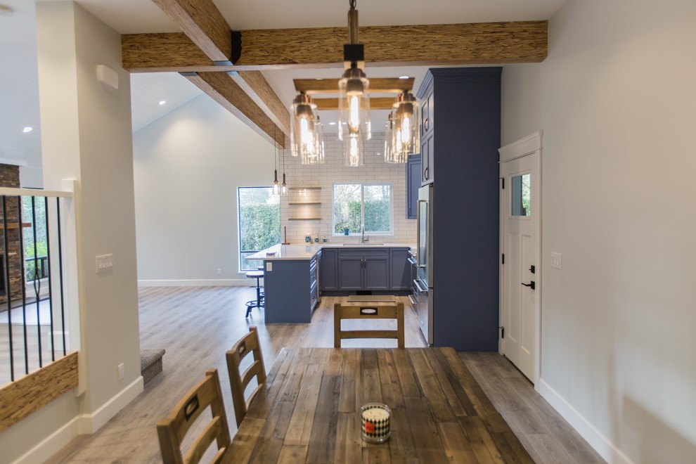 Foto di una sala da pranzo aperta verso la cucina minimalista di medie dimensioni con pareti bianche, pavimento in laminato e pavimento marrone