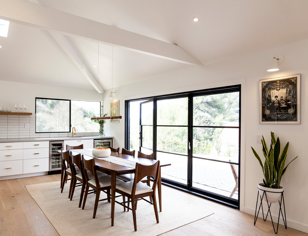 Ispirazione per una sala da pranzo aperta verso la cucina minimal di medie dimensioni con pareti bianche, parquet chiaro e pavimento marrone