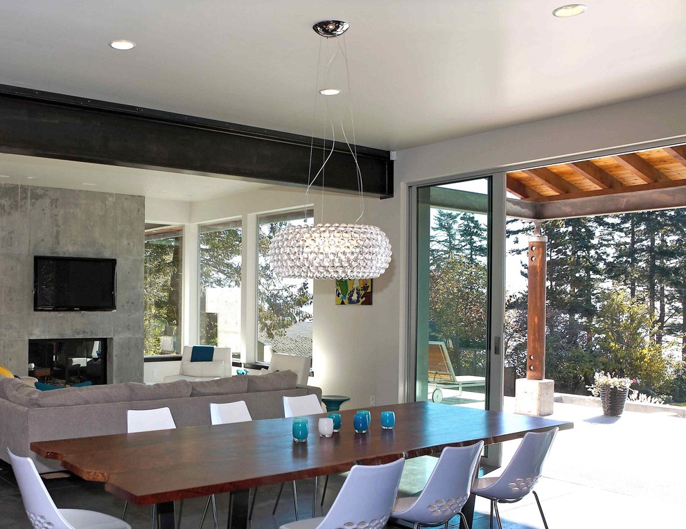 Inspiration for a medium sized contemporary open plan dining room in Seattle with white walls, concrete flooring, a standard fireplace, a concrete fireplace surround and grey floors.