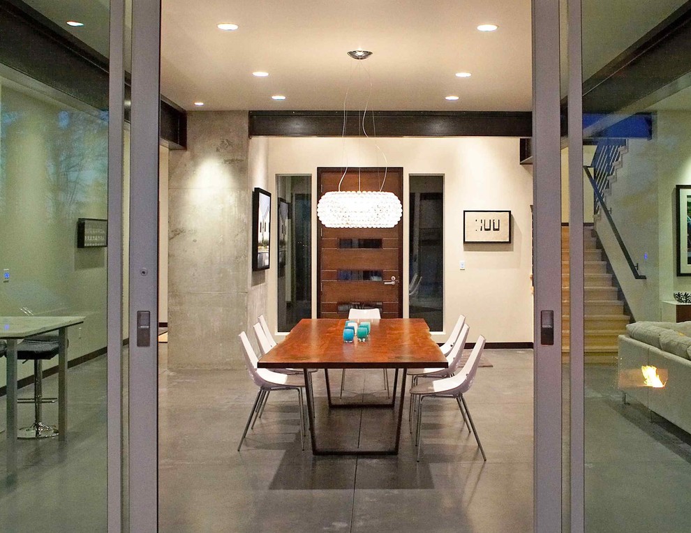Ispirazione per una sala da pranzo aperta verso la cucina minimalista di medie dimensioni con pareti bianche, pavimento in cemento e pavimento beige