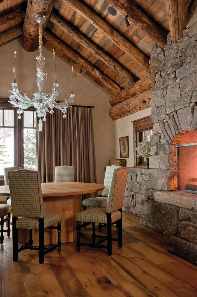 Immagine di una sala da pranzo stile rurale con pareti beige, pavimento in legno massello medio e cornice del camino in pietra