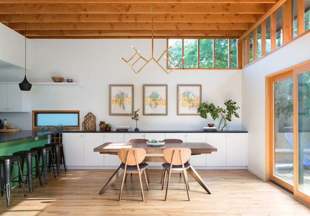 Modelo de comedor contemporáneo con paredes blancas y suelo de madera en tonos medios