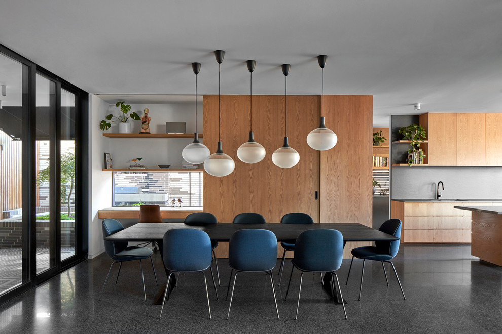 This is an example of a contemporary dining room in Melbourne with concrete flooring, a corner fireplace, a concrete fireplace surround and black floors.