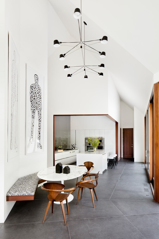 Aménagement d'une salle à manger ouverte sur le salon moderne avec un mur blanc et un sol gris.