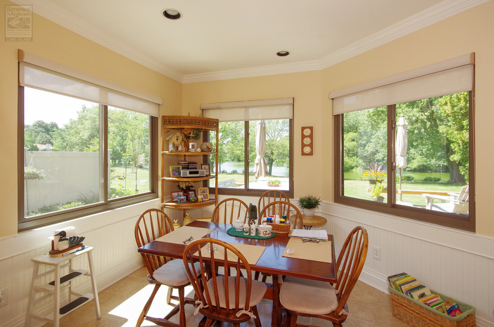 Immagine di una sala da pranzo aperta verso la cucina di medie dimensioni con pareti gialle, pavimento con piastrelle in ceramica, nessun camino, pavimento beige e boiserie