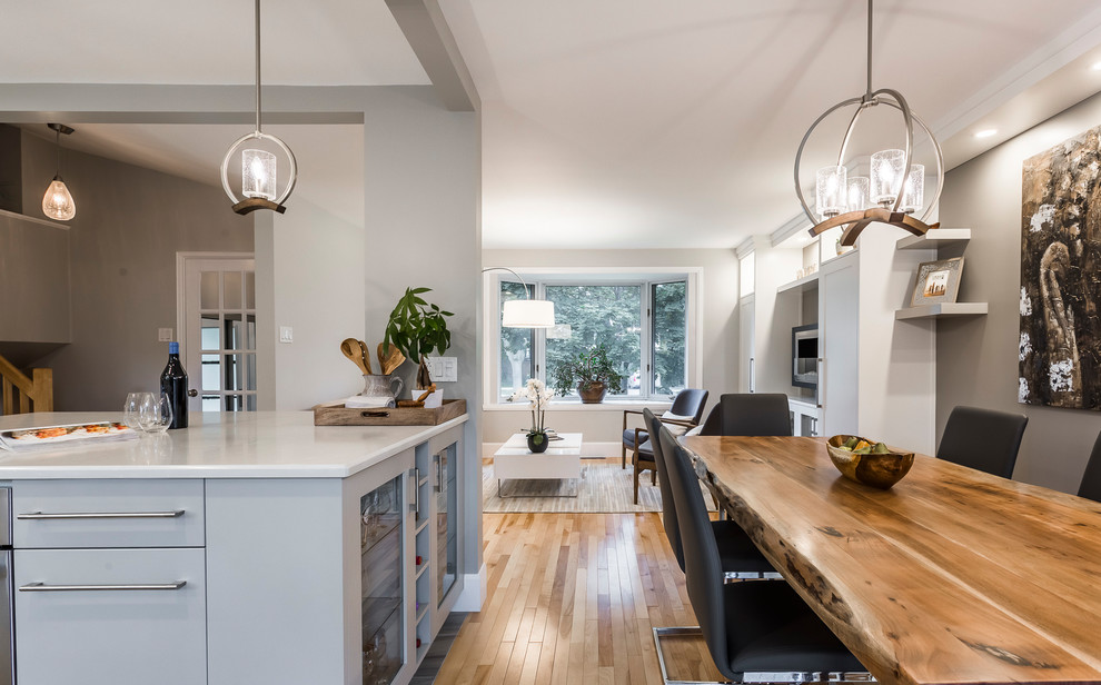 Immagine di una sala da pranzo aperta verso la cucina classica di medie dimensioni con pareti grigie, parquet chiaro, camino sospeso e pavimento beige