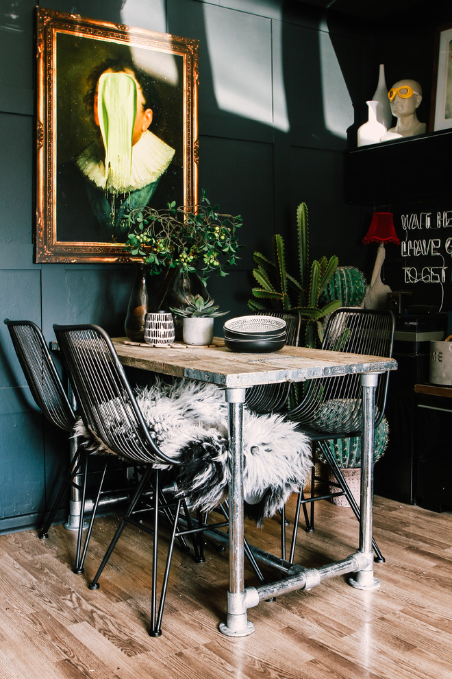 Diseño de comedor bohemio con paredes negras, suelo de madera en tonos medios y suelo marrón