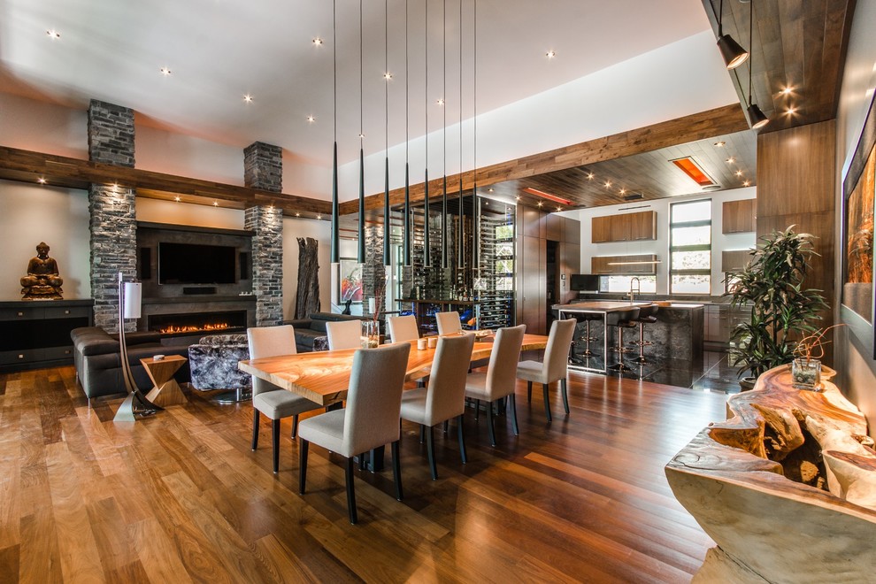 Aménagement d'une salle à manger ouverte sur le salon contemporaine avec un mur blanc, un sol en bois brun et une cheminée ribbon.
