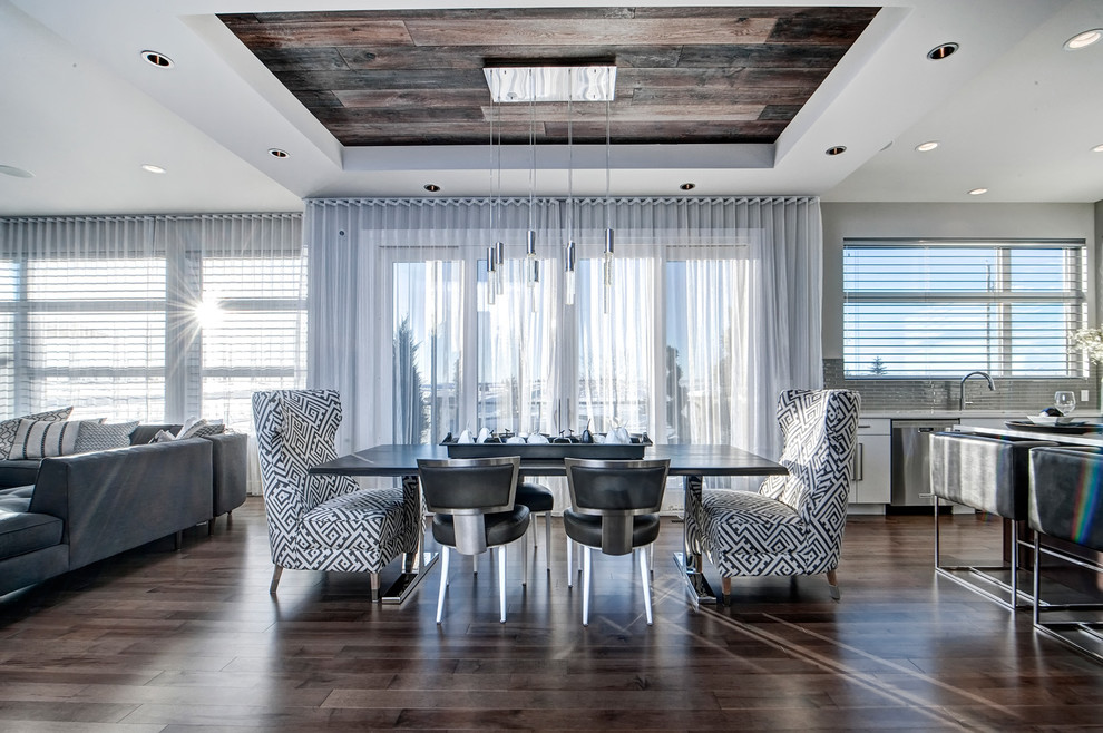 Cette image montre une salle à manger ouverte sur le salon design de taille moyenne avec un mur gris, un sol en bois brun, aucune cheminée et un sol gris.