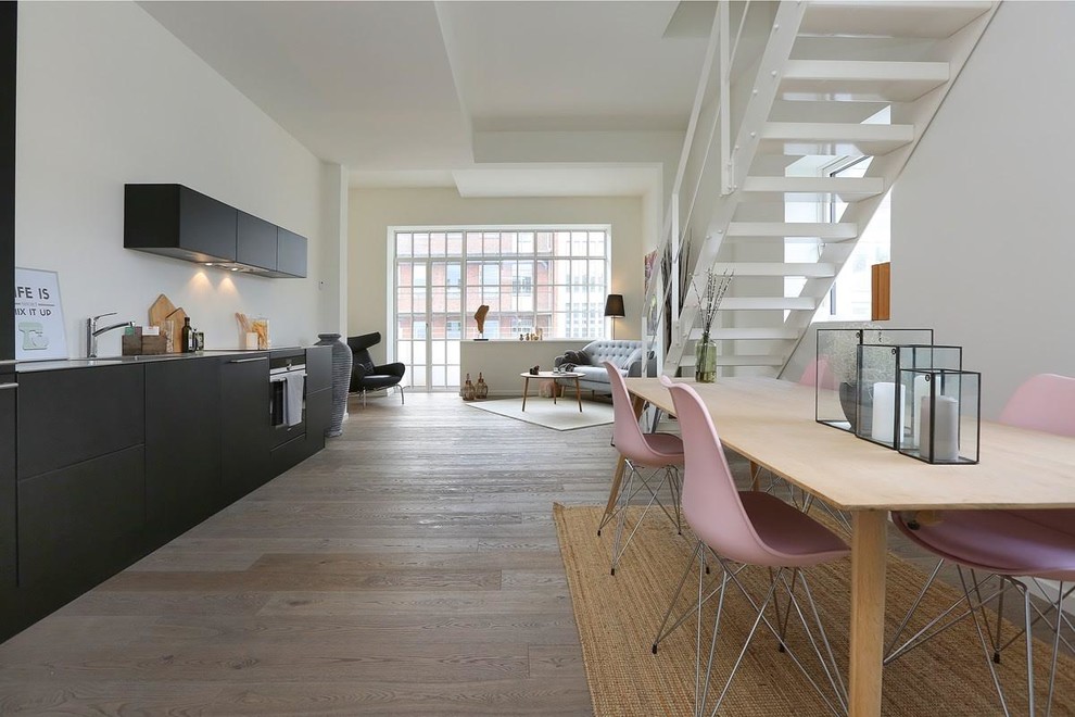 Aménagement d'une salle à manger ouverte sur le salon scandinave avec un mur blanc, parquet foncé et un sol marron.