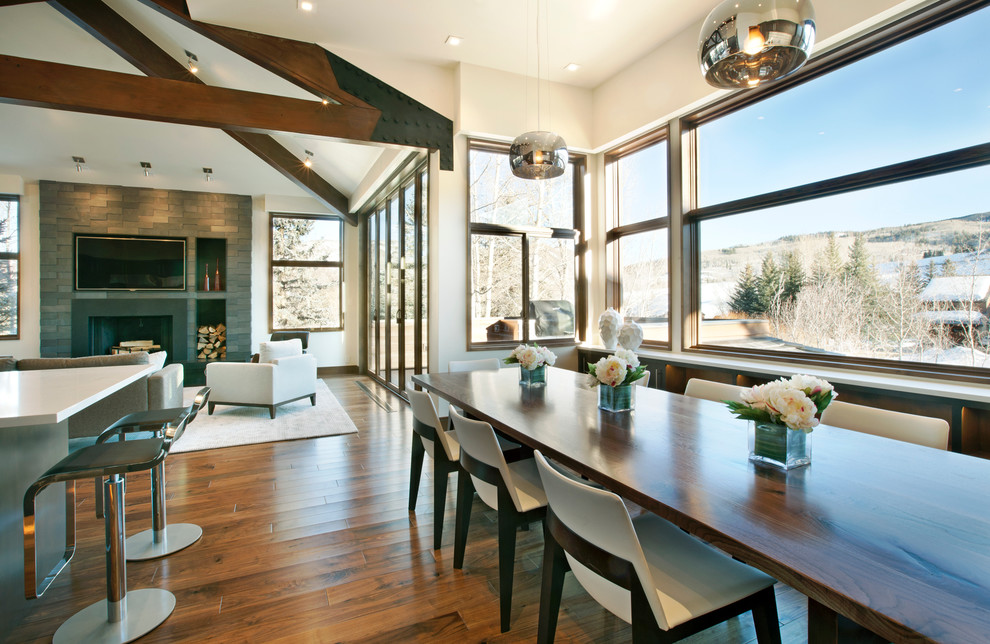Cette photo montre une grande salle à manger ouverte sur la cuisine tendance avec un mur beige et un sol en bois brun.