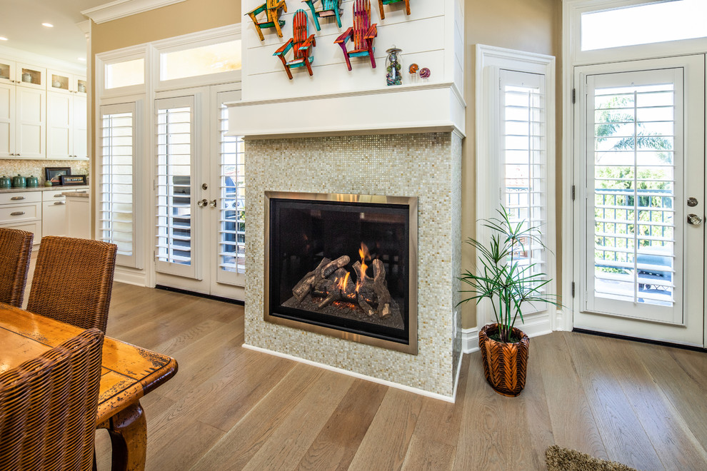 Example of a beach style kitchen/dining room combo design in San Diego with a standard fireplace and a tile fireplace