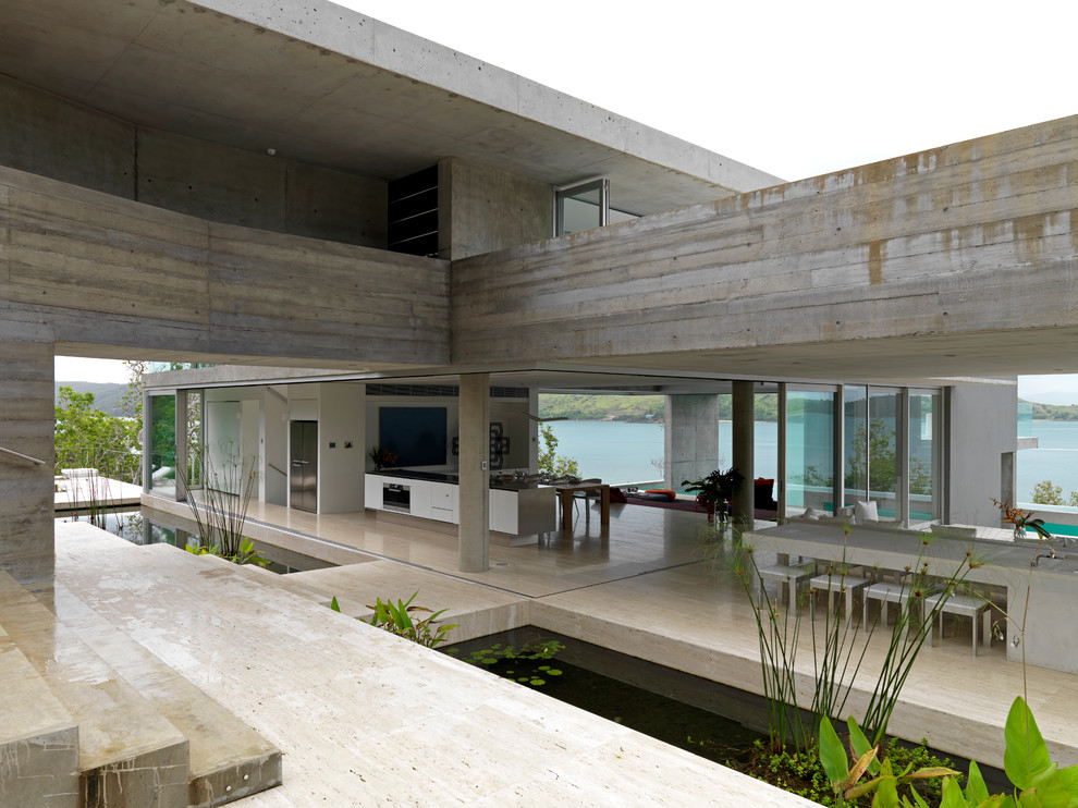 На фото: огромная гостиная-столовая в стиле лофт с серыми стенами, бетонным полом и бежевым полом без камина