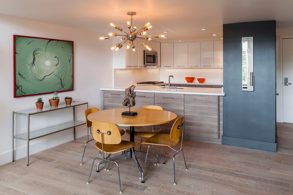 Réalisation d'une salle à manger ouverte sur la cuisine minimaliste de taille moyenne avec un mur blanc, un sol en bois brun, aucune cheminée et un sol gris.