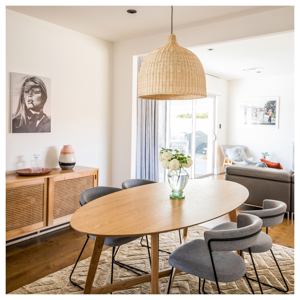 Ispirazione per una sala da pranzo aperta verso il soggiorno minimalista con pareti bianche, pavimento in legno massello medio e pavimento marrone