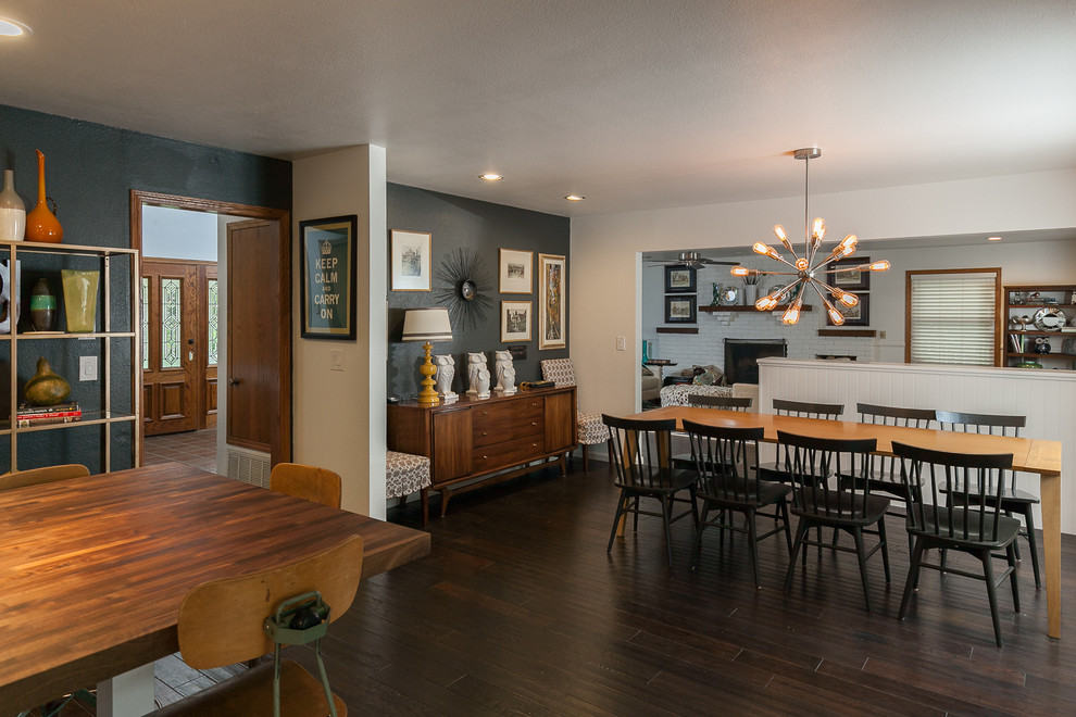 Cette photo montre une grande salle à manger ouverte sur la cuisine rétro avec un mur gris, parquet foncé, un sol marron et éclairage.