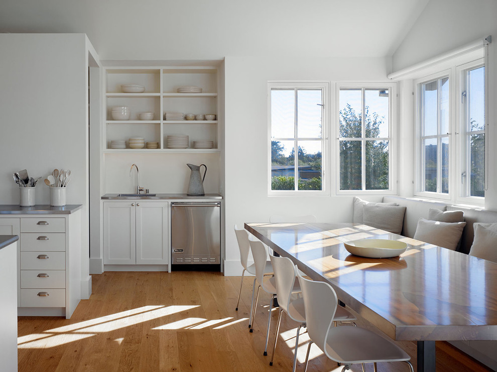 Immagine di una sala da pranzo aperta verso la cucina country con pareti bianche e pavimento in legno massello medio