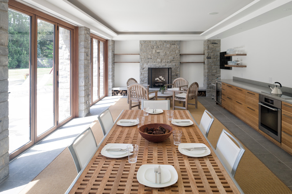 Стильный дизайн: кухня-столовая среднего размера в современном стиле с белыми стенами, полом из керамогранита, стандартным камином, фасадом камина из камня и серым полом - последний тренд