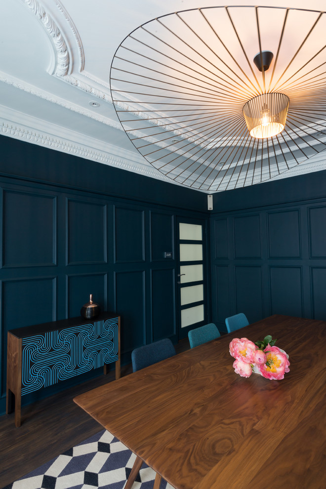 This is an example of a midcentury enclosed dining room in London with blue walls, dark hardwood flooring, a standard fireplace and a plastered fireplace surround.