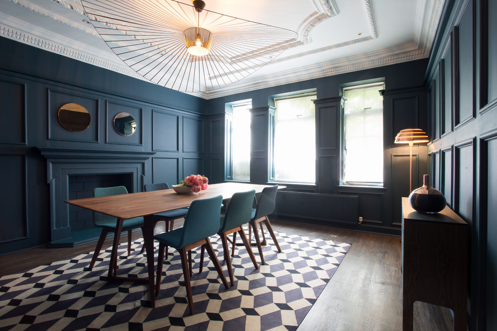 На фото: отдельная столовая в стиле неоклассика (современная классика) с синими стенами, темным паркетным полом, стандартным камином и фасадом камина из штукатурки с